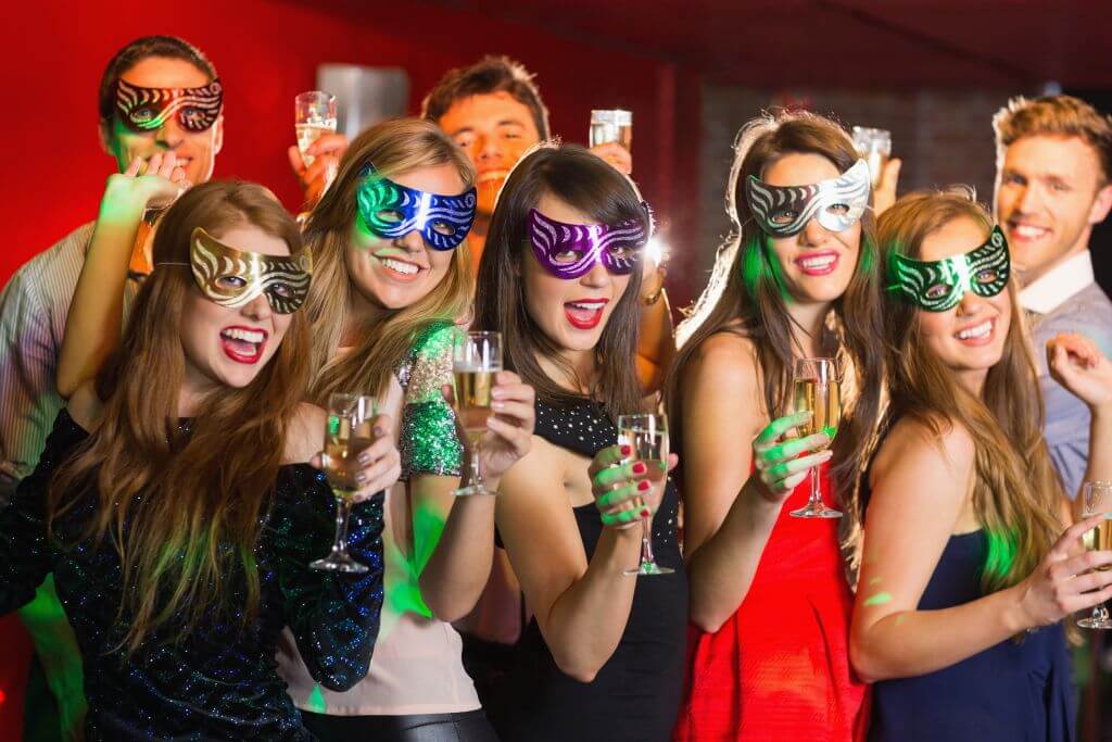 Friends in masquerade masks drinking champagne at the nightclub